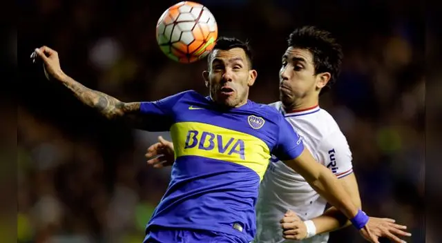Carlos Tévez disputa el balón con Jorge Fucile.