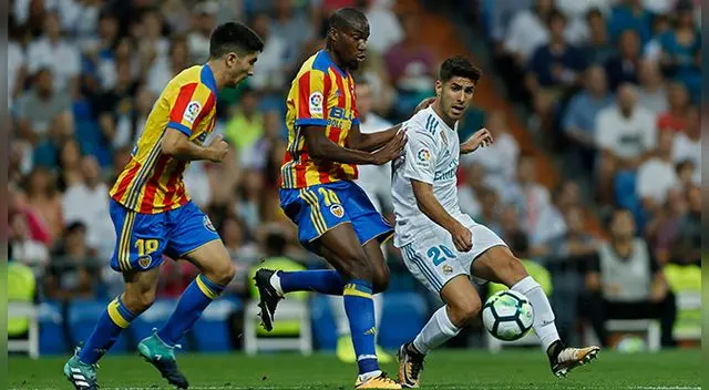 Marco Asensio disputa un balón con Kondogbia y Soler.