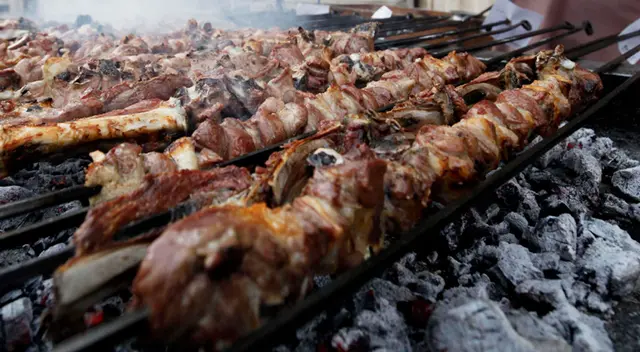 Hombre prepara carne asada en una carretera.