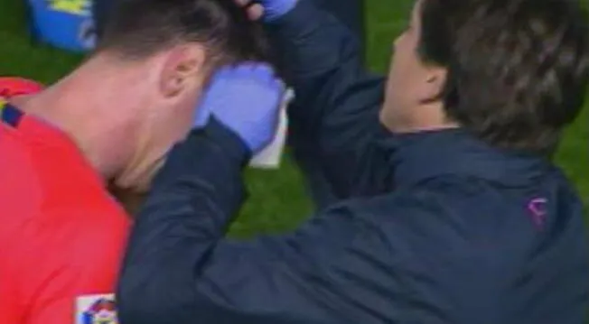 Lionel Messi siendo atentido por un médico del Barcelona tras recibir impacto de botella.