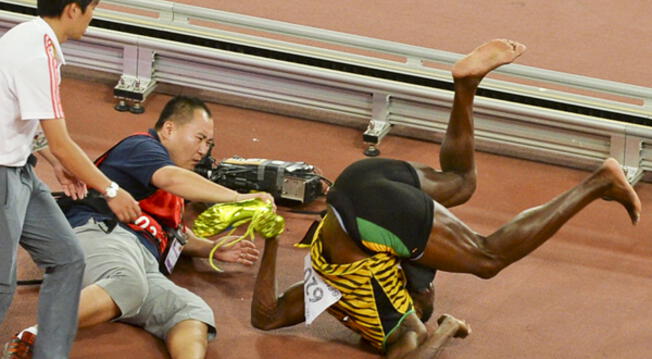 Usain Bolt cae tras el impacto con el camarógrafo en el Mundial de Atletismo de Pekín.