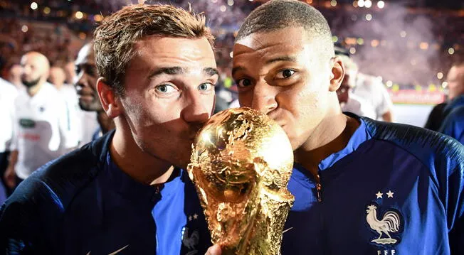 Antoine Griezmann y Kylian Mbappé besan el trofeo de la Copa del Mundo.
