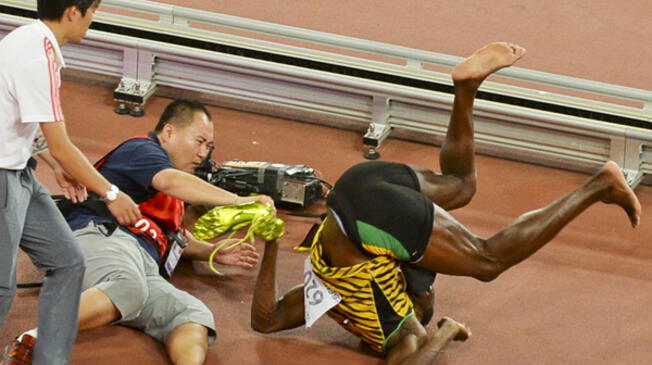 Usain Bolt cae tras el impacto con el camarógrafo en el Mundial de Atletismo de Pekín.