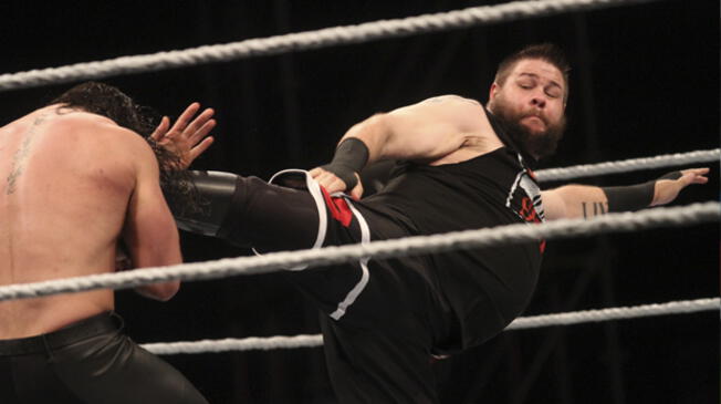 Kevin Owens ensaya una patada a Roman Reigns.